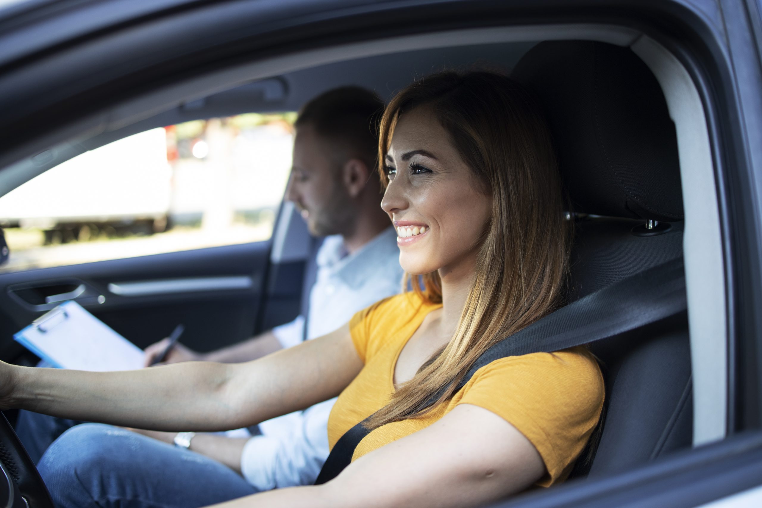 close-up-view-female-student-driving-car-instructor-holding-checklist-scaled.jpg